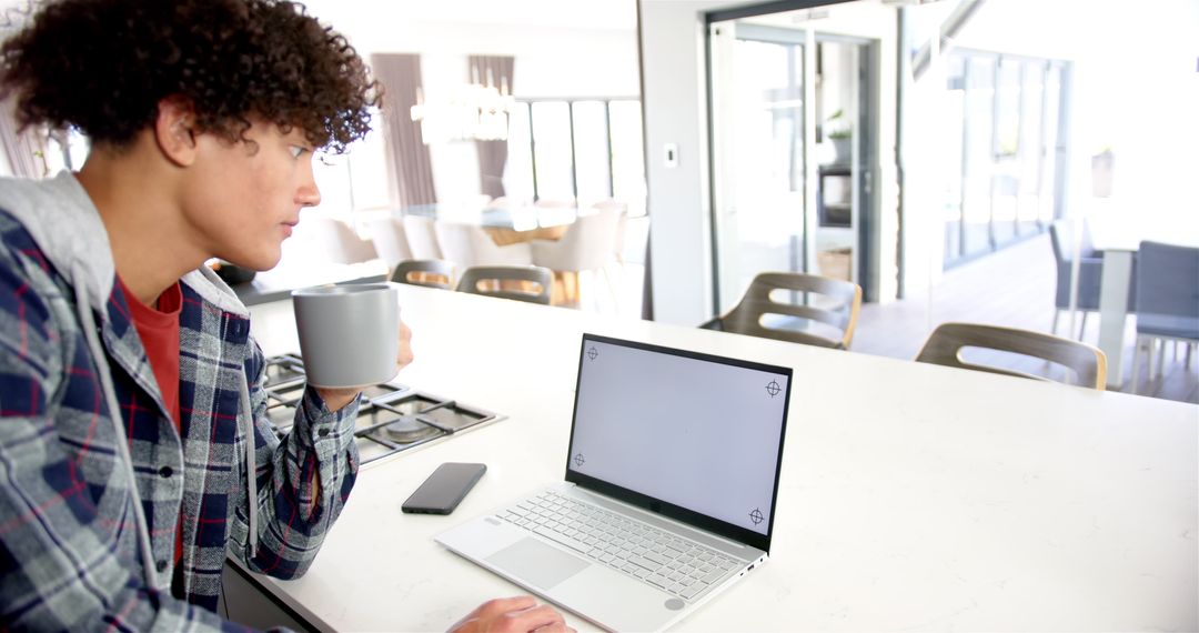 Man Enjoying Coffee While Working Remotely in Modern Kitchen