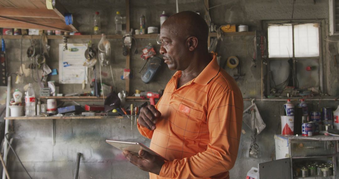 African American mechanic using digital tablet in garage workshop - Free Images, Stock Photos and Pictures on Pikwizard.com