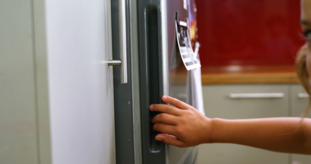 A child reaches out to open a refrigerator door, with copy space - Free Images, Stock Photos and Pictures on Pikwizard.com
