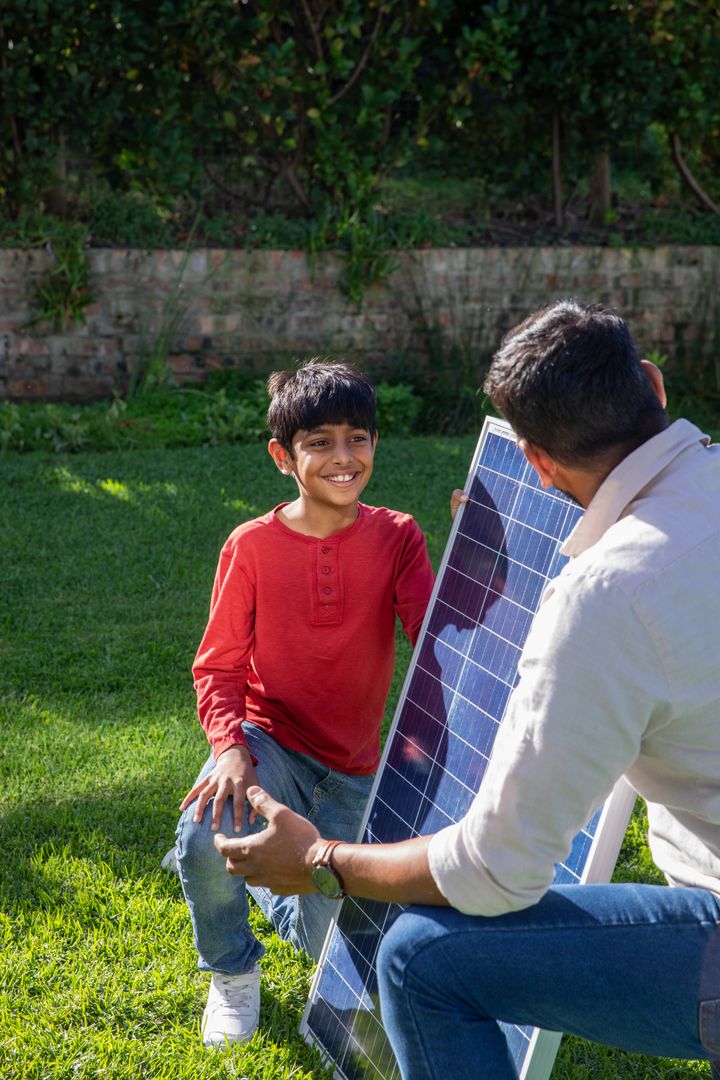 Father and Son Learning About Solar Panel on Green Lawn