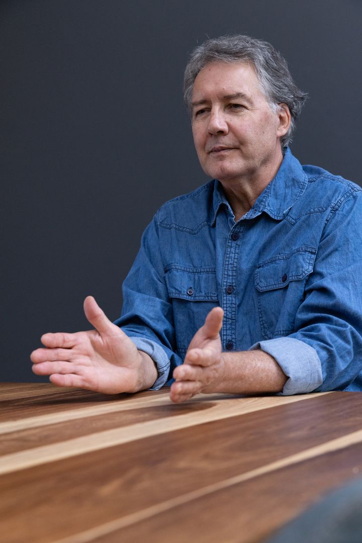 Senior Man in Discussion at Modern Wooden Table in Denim Attire