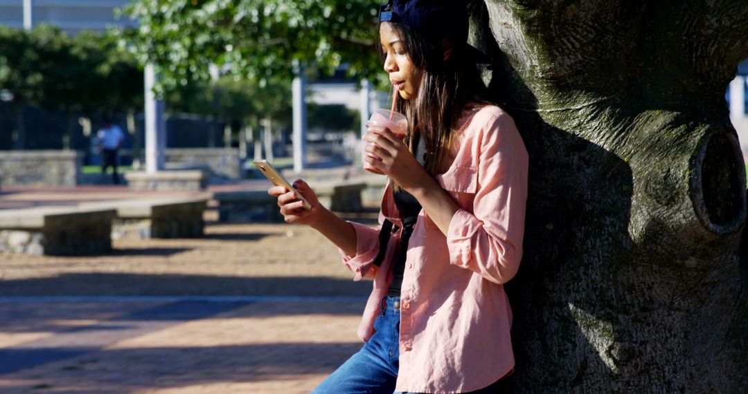 Young Woman Drinking Juice and Using Phone in Park - Free Images, Stock Photos and Pictures on Pikwizard.com