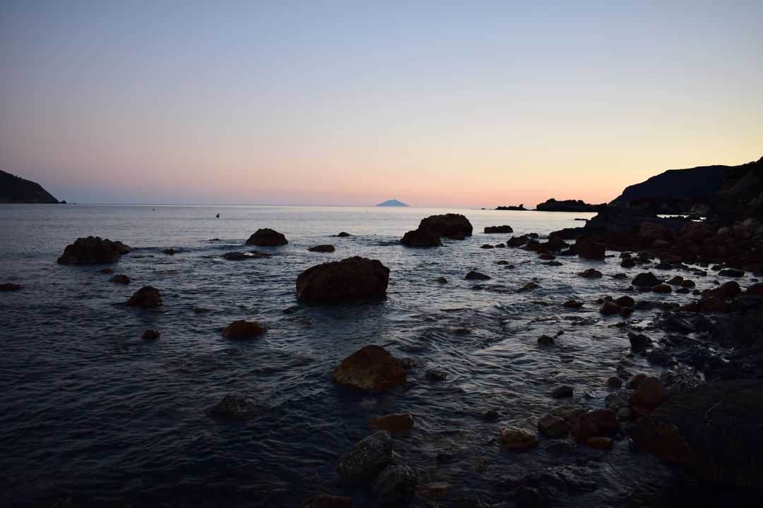 Serene Coastal Sunset with Rocky Shore and Calm Sea - Free Images, Stock Photos and Pictures on Pikwizard.com