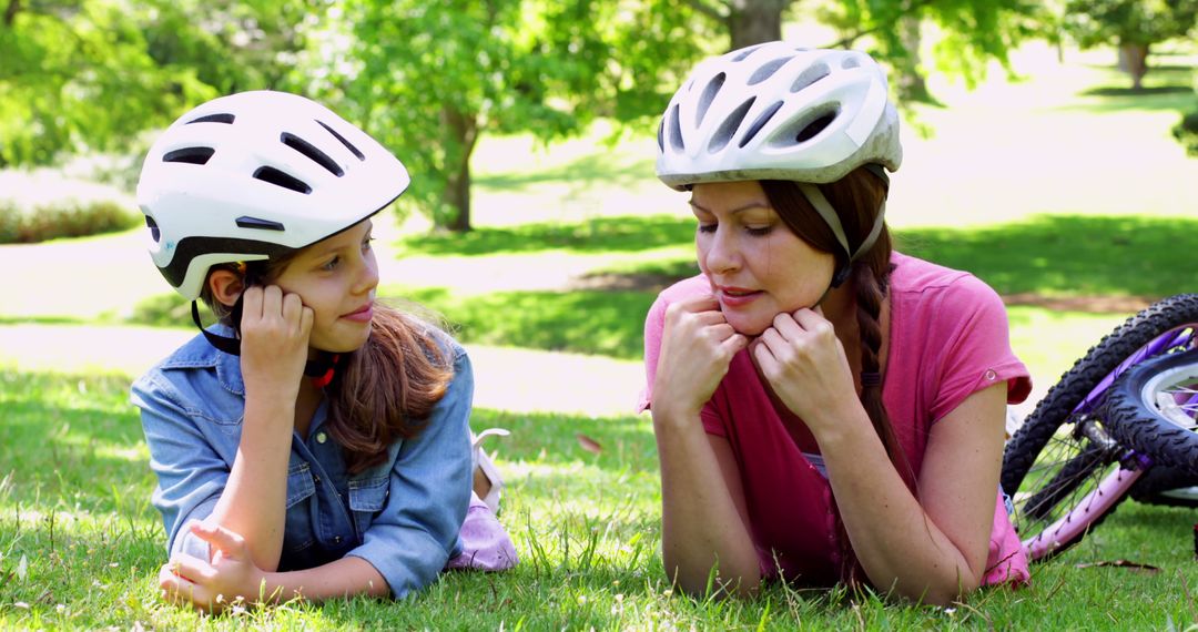 Mother and Daughter Relaxing on Grass with Bicycles and Helmets - Free Images, Stock Photos and Pictures on Pikwizard.com