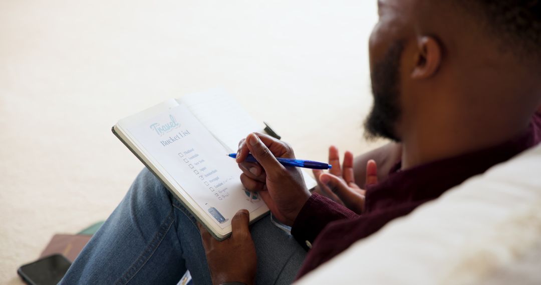 Man Writing Travel Bucket List in Relaxed Home Setting