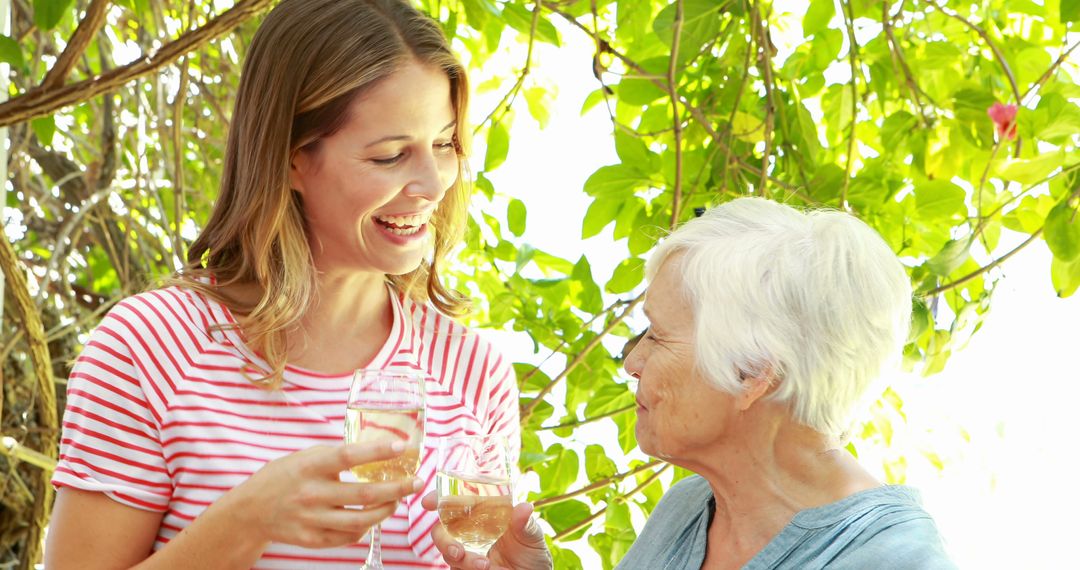 Women Enjoying White Wine Together Outdoors in Lush Garden - Free Images, Stock Photos and Pictures on Pikwizard.com