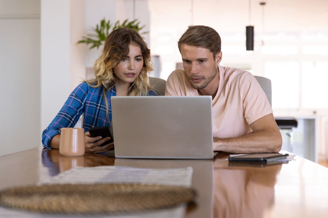 Couple Using Laptop Together at Home with Smartphones and Mug