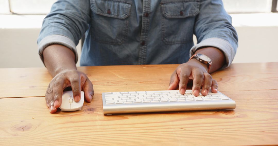 Close-Up of Hands Typing on Wireless Keyboard on Wooden Desk