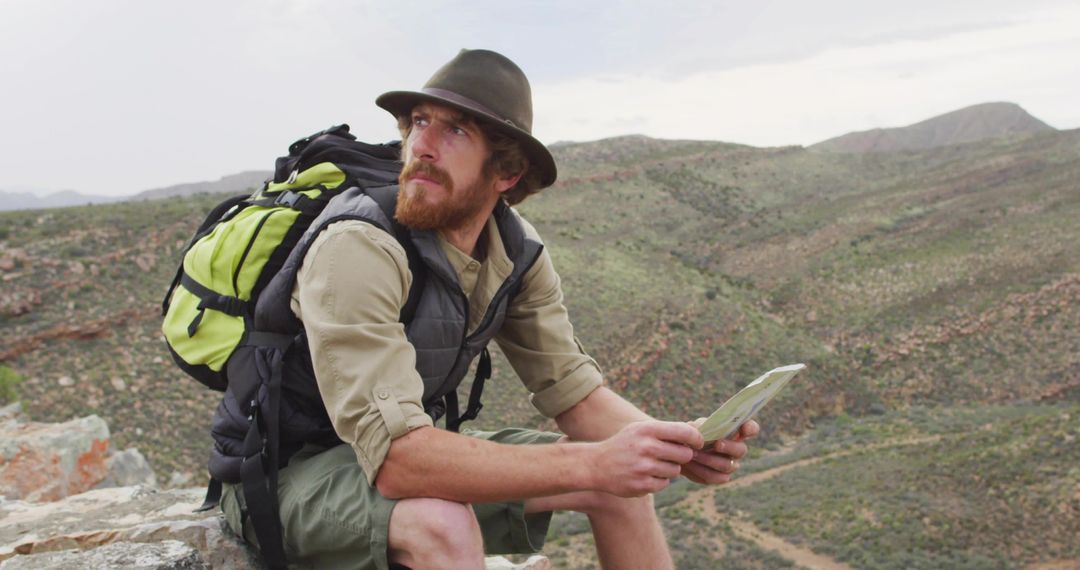 Explorer Reading Map on Rocky Cliff Edge in Vast Wilderness