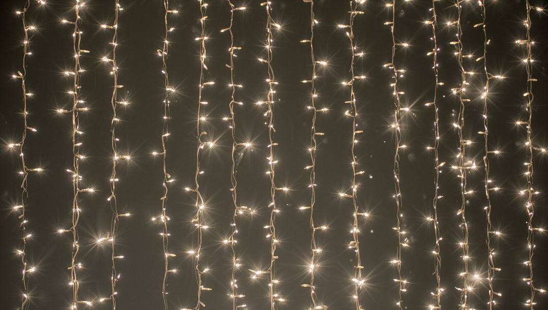 Warm White LED Curtain Lights Creating Vertical Starburst Glow for Festive Backdrops