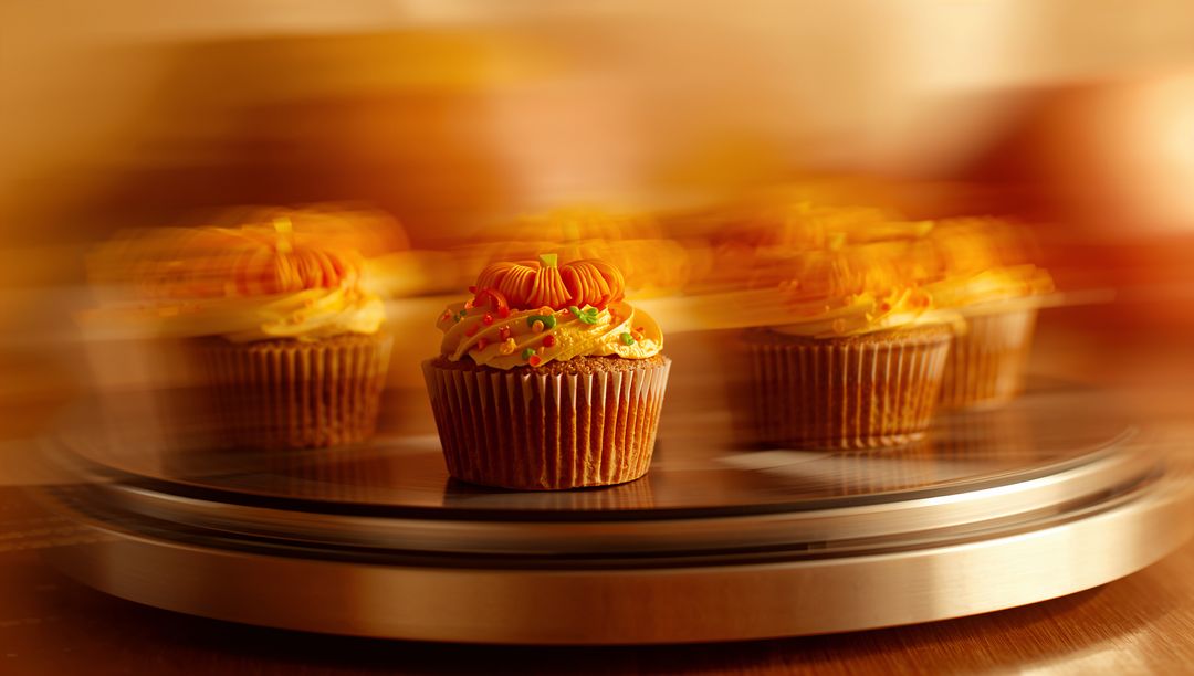 Festive Pumpkin Cupcake on Rotating Cake Stand in Warm Lighting