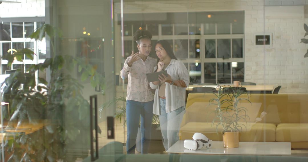 Businesswomen Collaborate Using Tablet in Modern Office