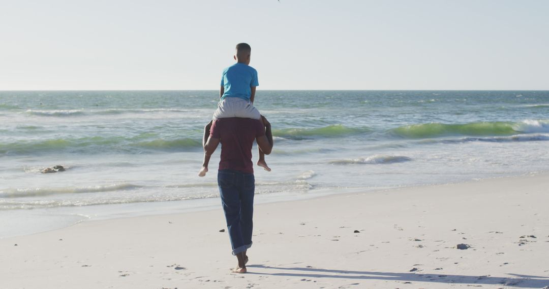 Father Carrying Son on Shoulders Walking on Sandy Beach - Free Images, Stock Photos and Pictures on Pikwizard.com