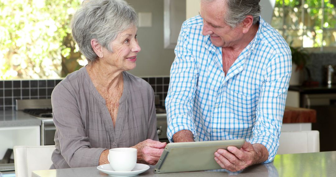 Senior Couple Enjoying Conversation Over Digital Tablet in Kitchen
