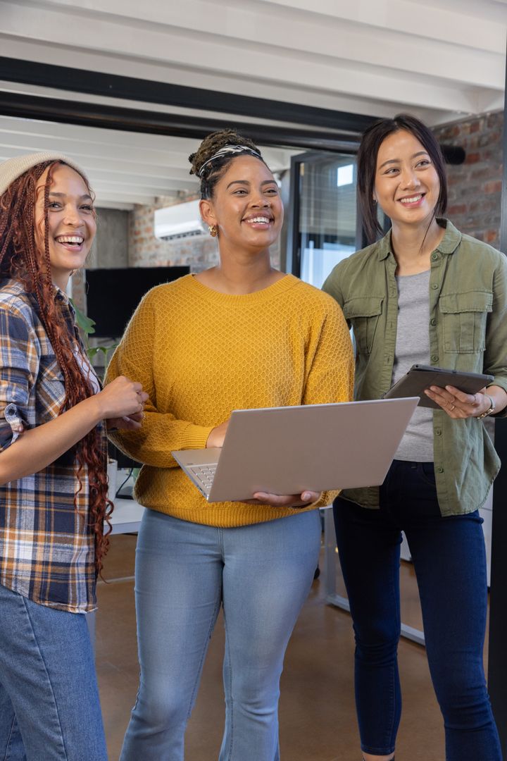 Diverse Female Colleagues Collaborating with Technology in Modern Office
