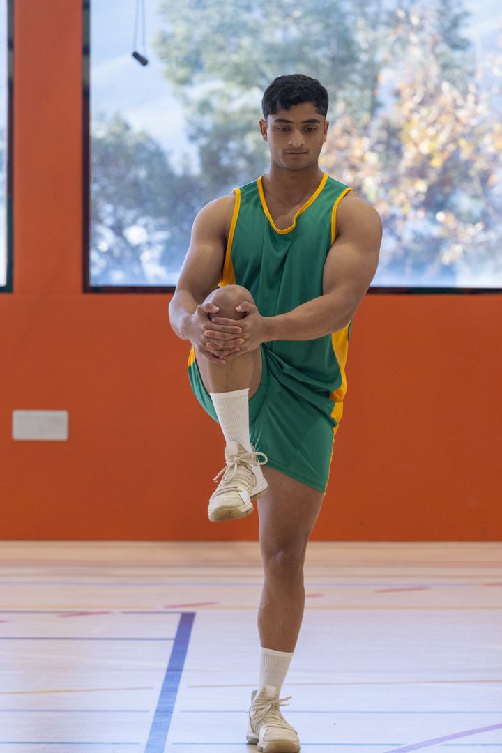 Muscular Athlete Doing Stretch Routine in Gymnasium