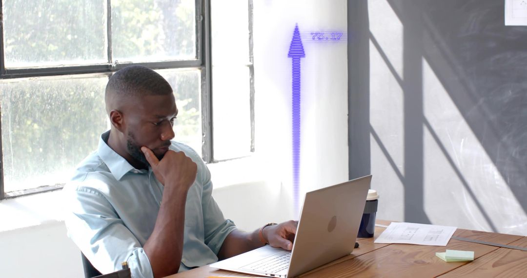 Focused Professional Analyzing Laptop Data Near Sunlit Office Window