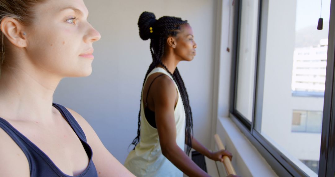 Two Women Focusing on Window Views During Indoor Exercise - Free Images, Stock Photos and Pictures on Pikwizard.com