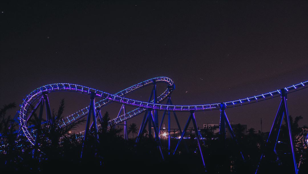 Illuminated Roller Coaster Loops Radiating Purple LED Lights at Night