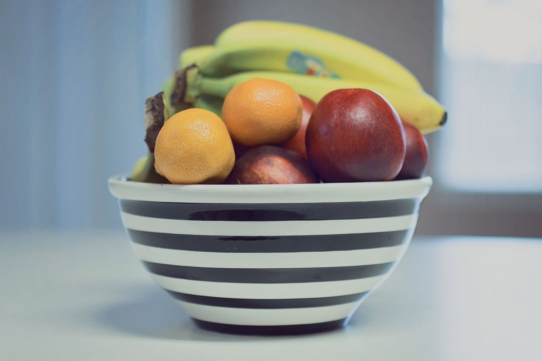 Displaying Black and White Striped Bowl Filled with Bananas Oranges and Nectarines
