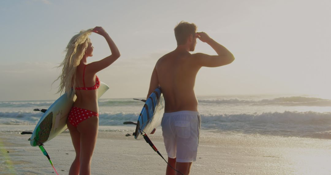 Couple Standing with Surfbords on Sunlit Beach