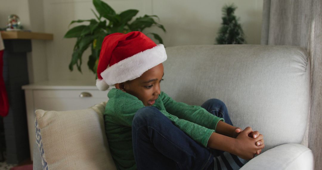 Cute Kid Relaxing on Sofa Wearing Santa Hat during Christmas Season - Free Images, Stock Photos and Pictures on Pikwizard.com