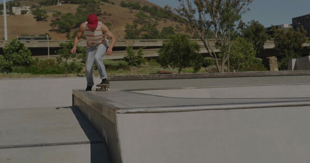 Skateboarder Dropping In From Ledge at Urban Skatepark Wearing Red Cap