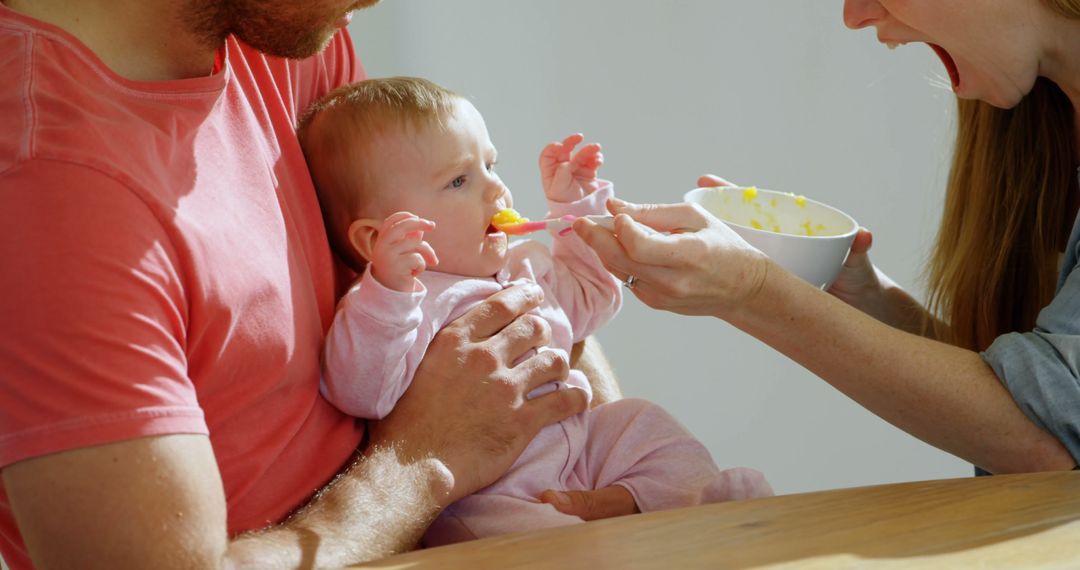 Parents Feeding Their Baby Solid Food at Home, Bonding Mealtime - Free Images, Stock Photos and Pictures on Pikwizard.com