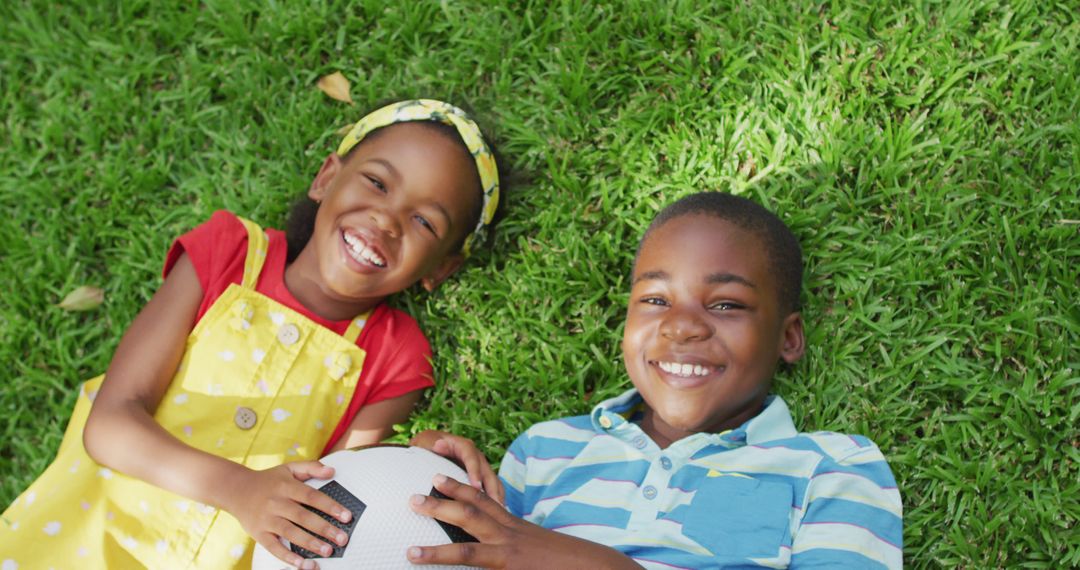 Smiling Brother and Sister Lying on Grass with Soccer Ball - Free Images, Stock Photos and Pictures on Pikwizard.com