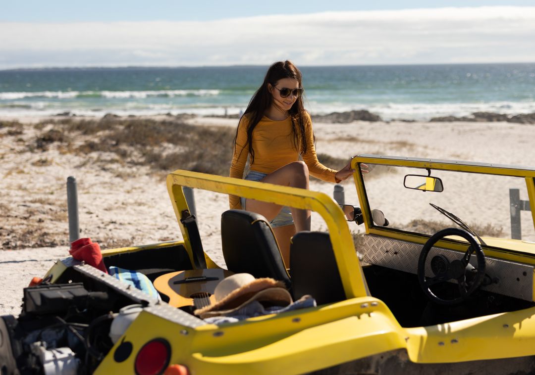 Woman Enjoying Beach Day with Yellow Dune Buggy by Ocean