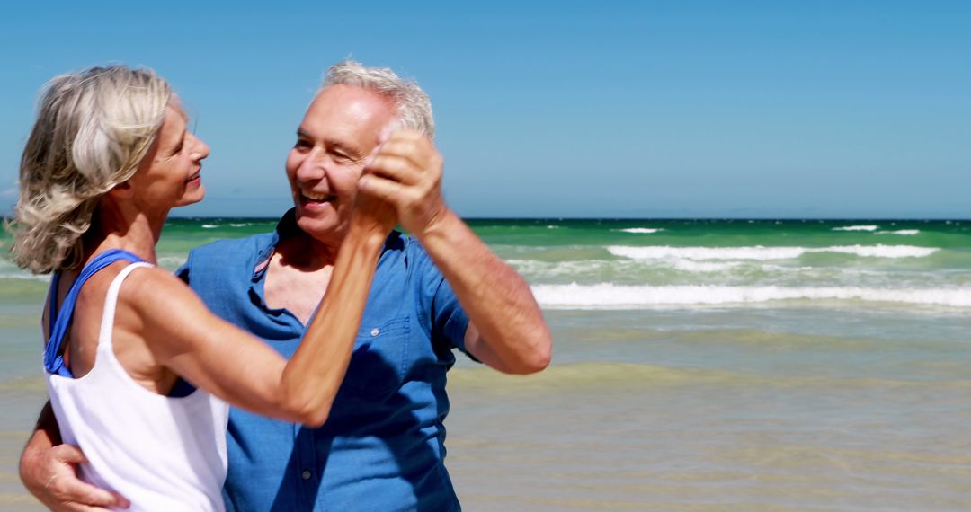 Joyful Senior Couple Dancing on a Sunny Beach - Free Images, Stock Photos and Pictures on Pikwizard.com