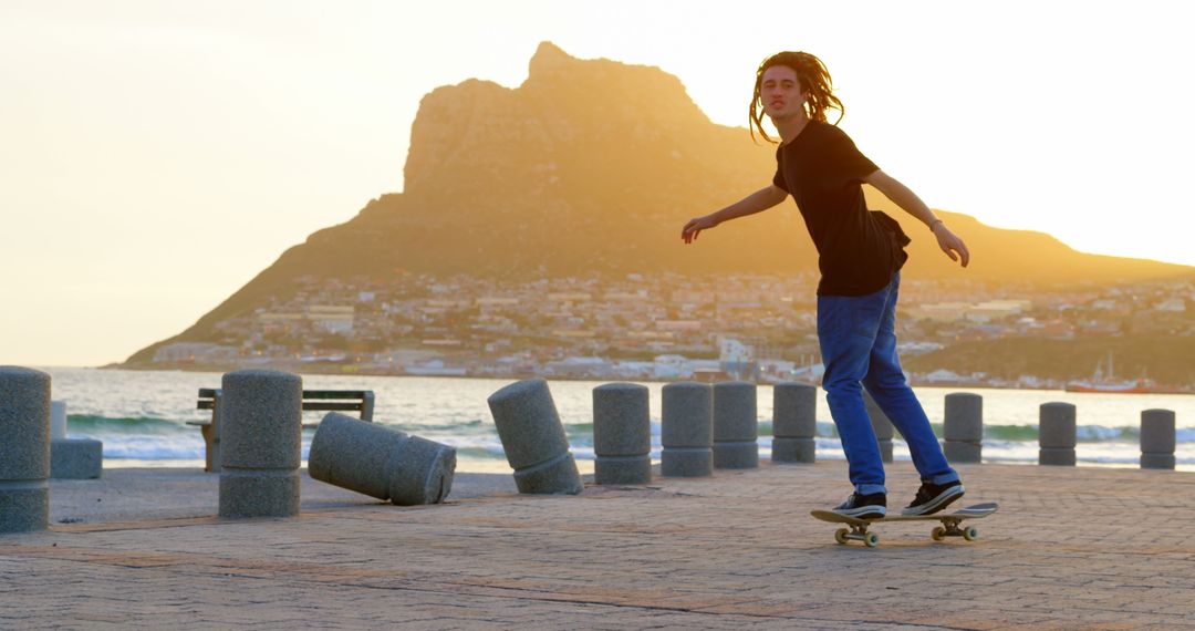 Teenager Skateboarding Along Seaside at Sunset with Mountain in Background - Free Images, Stock Photos and Pictures on Pikwizard.com