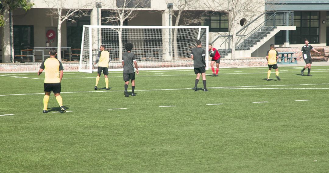Soccer Players Strategizing Near Goal in Competitive Match