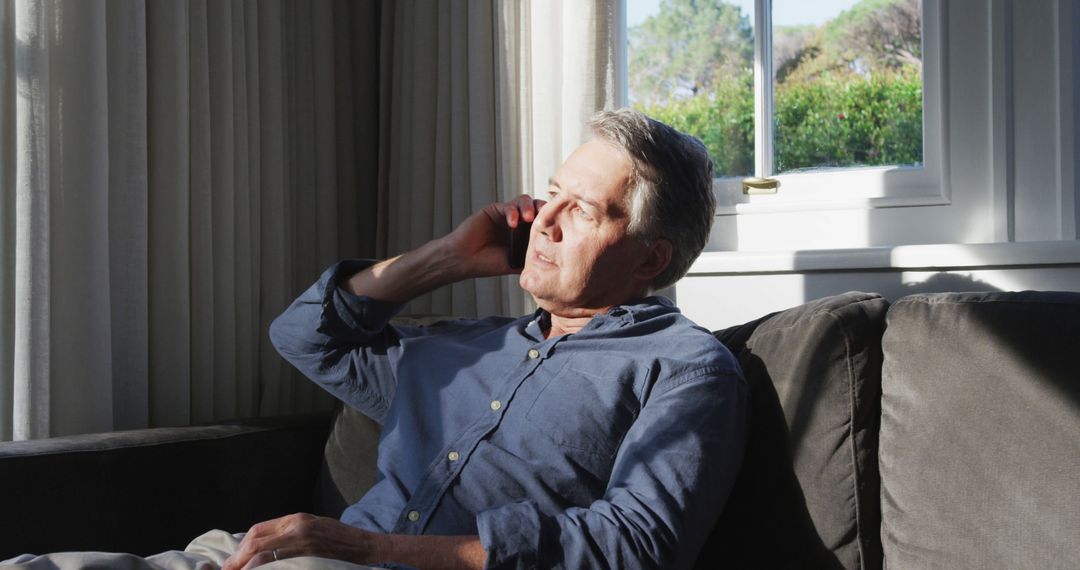 Middle-aged Man Talking on Phone in Sunlit Living Room - Free Images, Stock Photos and Pictures on Pikwizard.com