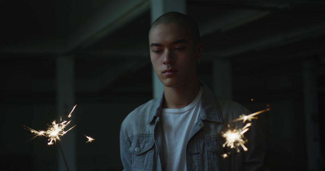 Young Man Holding Sparklers in Dark Room - Free Images, Stock Photos and Pictures on Pikwizard.com