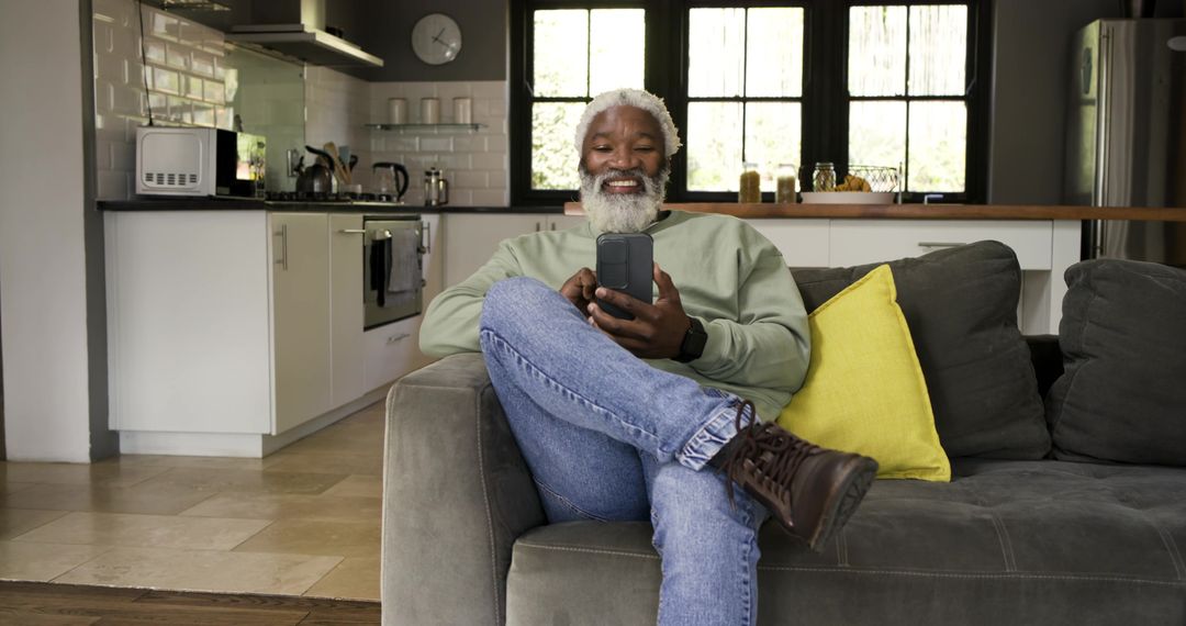 Senior Man Relaxing with Smartphone on Stylish Sofa at Home
