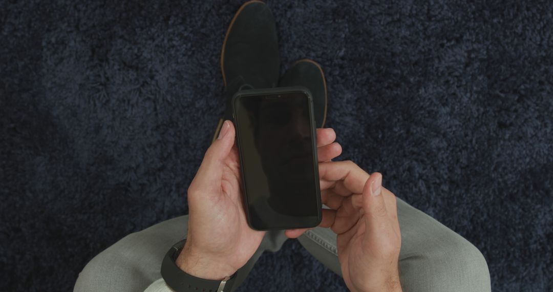 Man Sitting on Carpet Holding Smartphone with Blank Screen - Free Images, Stock Photos and Pictures on Pikwizard.com