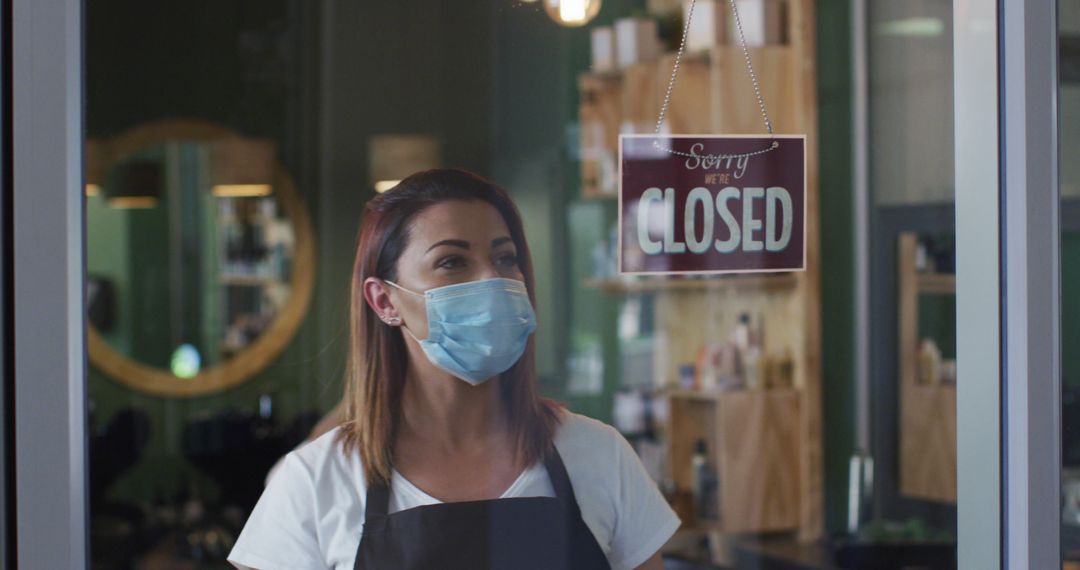 Female shop owner wearing mask hanging closed sign in door - Free Images, Stock Photos and Pictures on Pikwizard.com