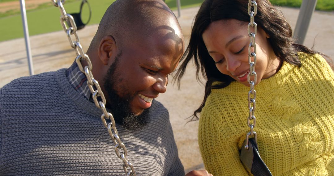 Joyful Couple Enjoying Smartphone at Park on Warm Sunny Day