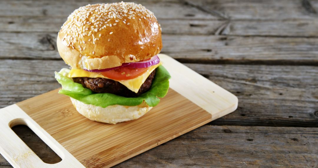 Delicious Cheeseburger with Vegetables on Wooden Cutting Board - Free Images, Stock Photos and Pictures on Pikwizard.com