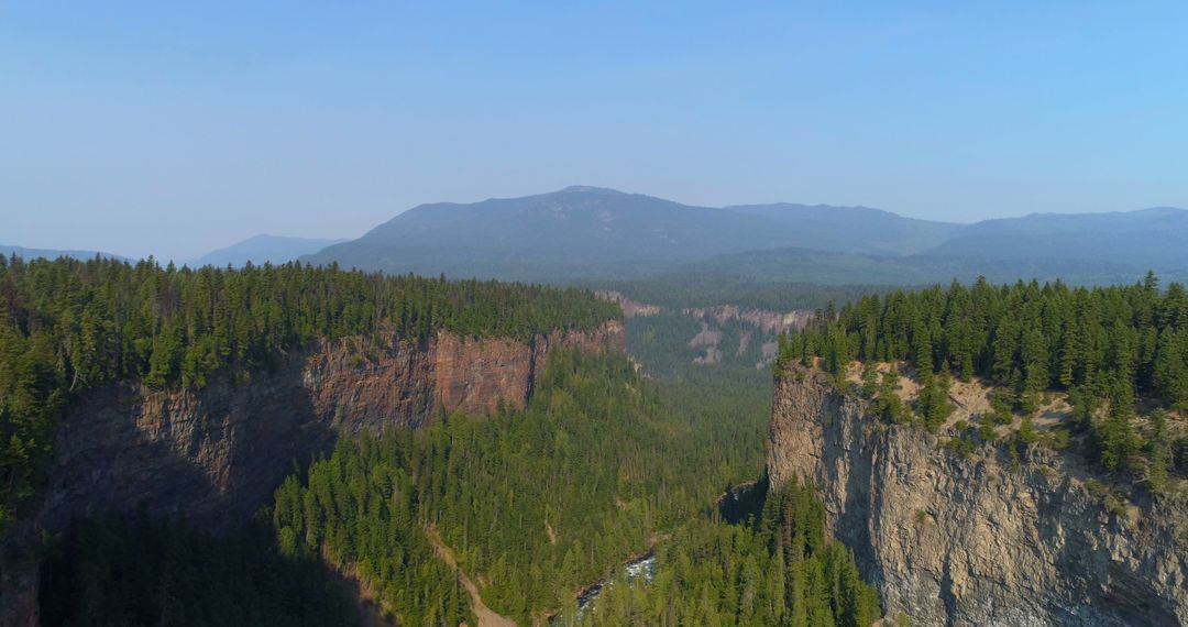 Aerial View of Forested Mountains with Rocky Cliffs on Clear Day - Free Images, Stock Photos and Pictures on Pikwizard.com