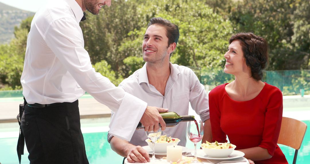 Waiter Serving Wine to Smiling Couple Dining Outdoors by Pool - Free Images, Stock Photos and Pictures on Pikwizard.com