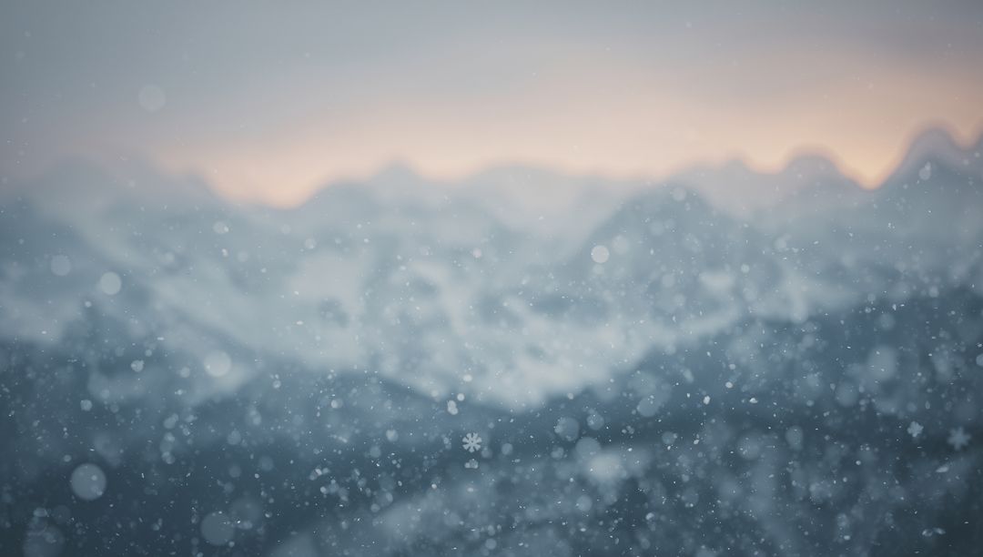 Drifting snow over hazy alpine ridgelines at dawn with soft bokeh horizon glow