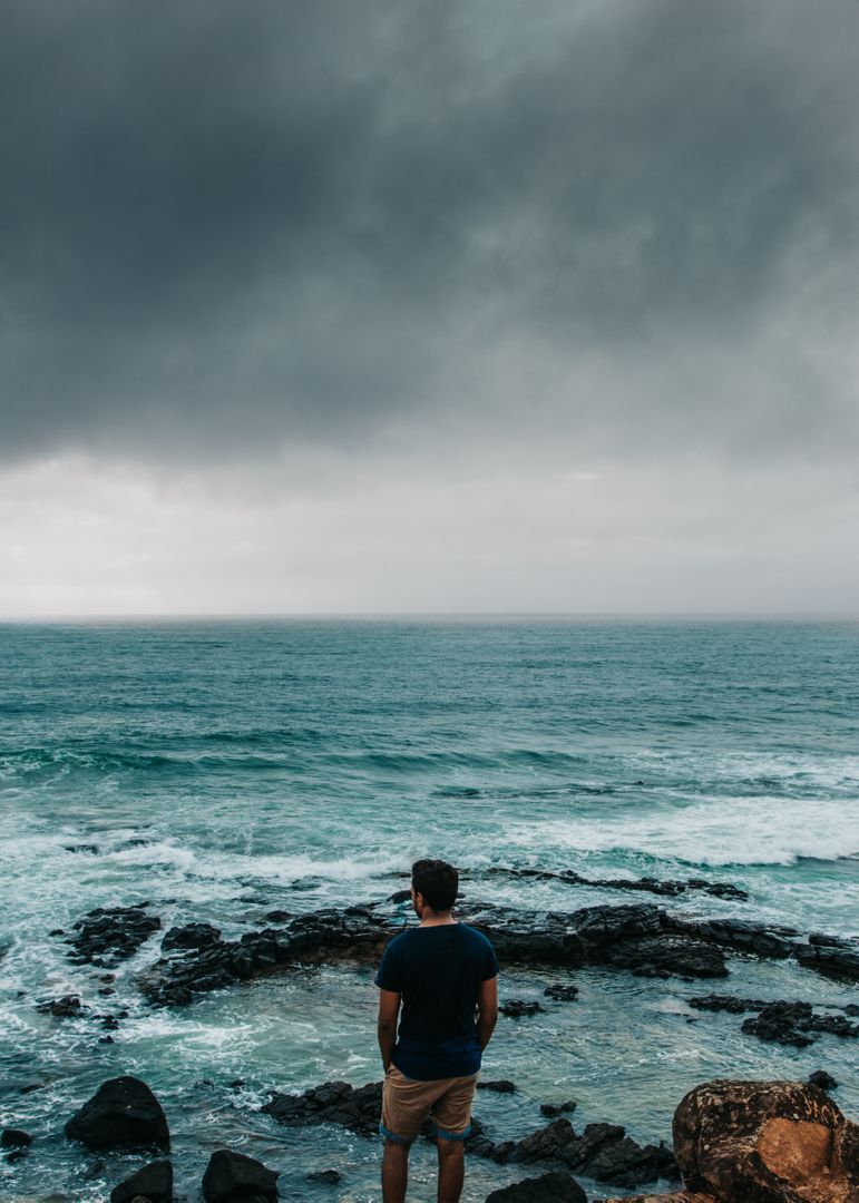 Man Reflecting Near Ocean Under Stormy Sky - Free Images, Stock Photos and Pictures on Pikwizard.com