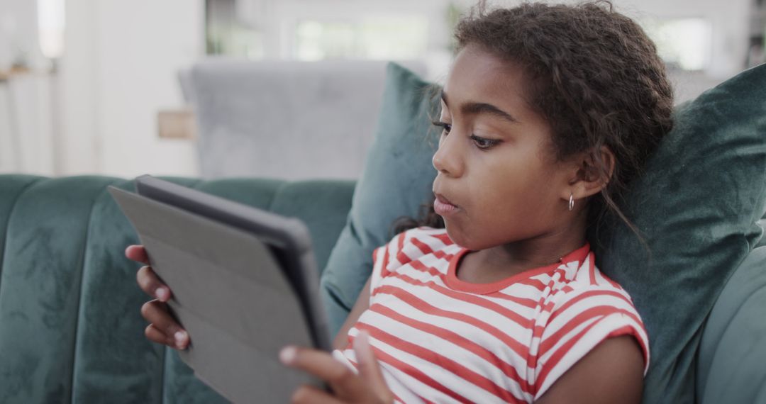 Young girl using tablet on couch for education or entertainment - Free Images, Stock Photos and Pictures on Pikwizard.com