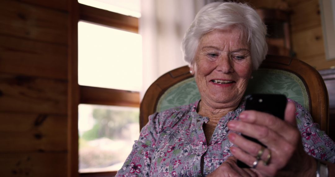 Senior Woman Smiling While Using Smartphone in Cozy Home