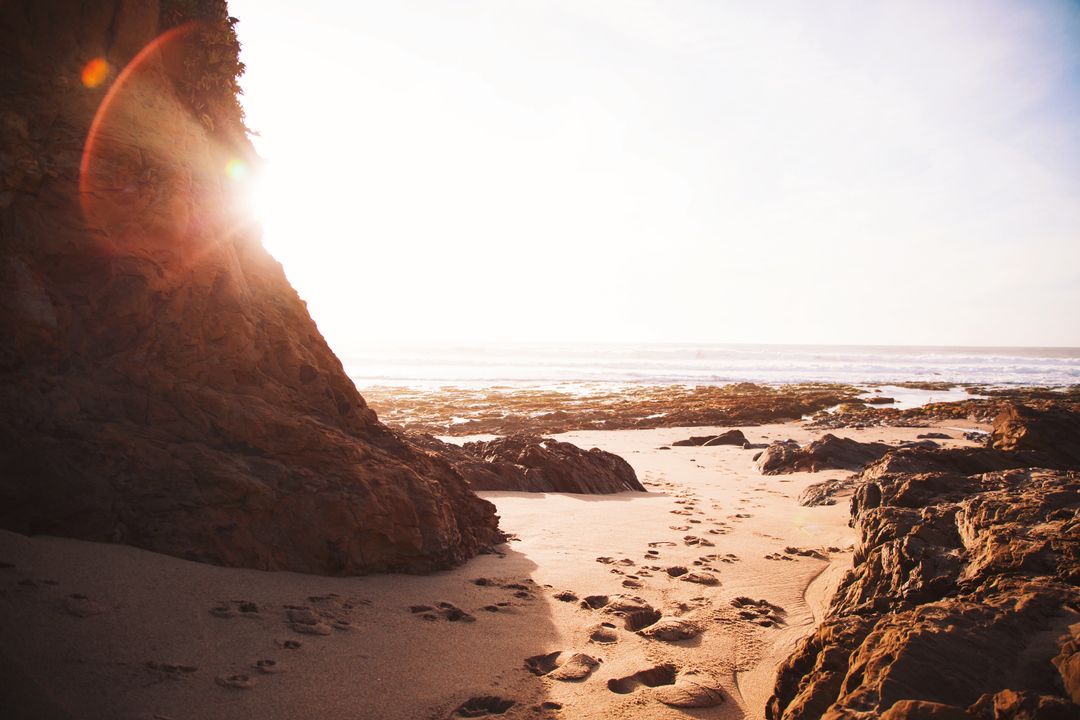 Sunlit Rocky Beach with Footprints Leading to Tidal Pools during Golden Hour