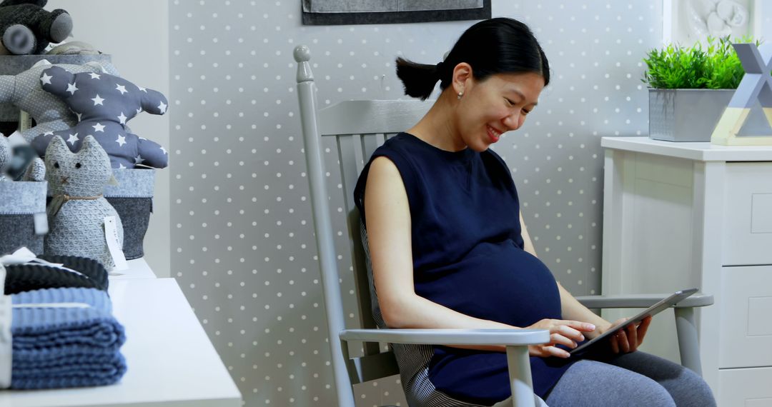 Pregnant woman relaxing on rocking chair using digital tablet in nursery - Free Images, Stock Photos and Pictures on Pikwizard.com