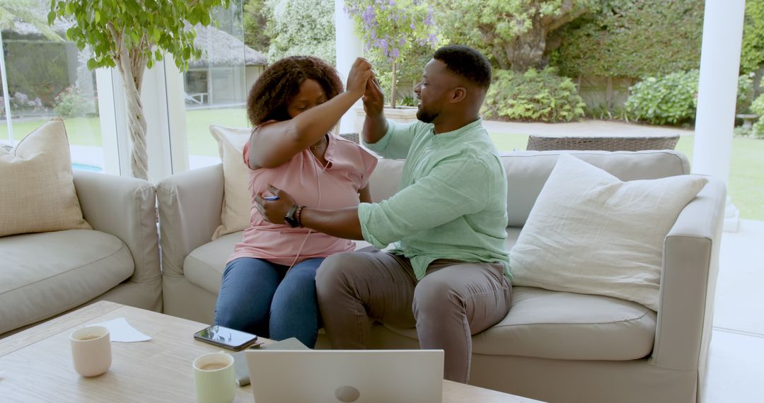 Joyful Couple Dancing Together at Home on Sofa