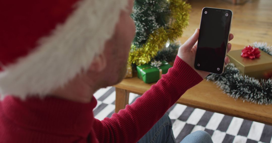 Man in Santa Hat Holding Smartphone During Christmas Celebration - Free Images, Stock Photos and Pictures on Pikwizard.com